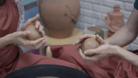 A close-up view of the hands of a man and woman sculpting clay. Stock Footage 128577773