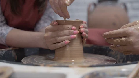 A close-up view of the hands of a man and woman sculpting clay. Stock Footage 128577977