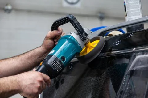 Close-up view on the hands of a man worker who holds a tool polisher for poli Stock Photos