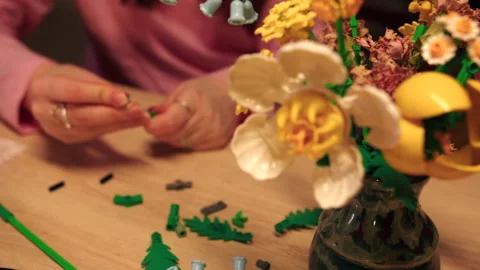 Close view of hands meticulously assembling unique flower arrangement in vase Stock Footage 335780349