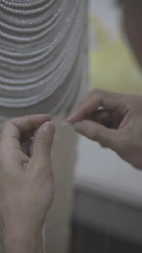 A close-up view of hands meticulously working on a beaded design, showcasing Stock Footage 332164220