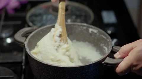 A close up view of hands mixing cornmeal porridge with thick cheese slices 스톡 동영상 346510370