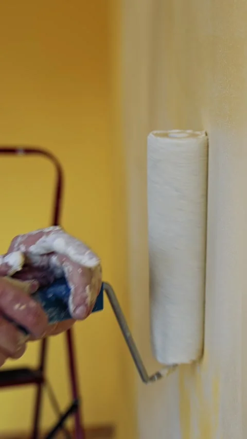 A close-up view of hands painting a room in yellow with a roller, preparing.. Stock Footage 337634698