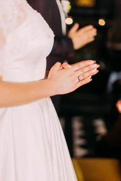 The close-up view of the hands of the praying bride. Stock Photos