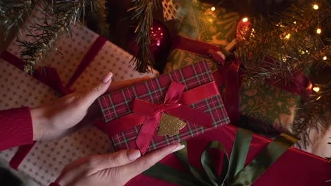 Close-up view of hands putting Christmas gift under the xmas tree Stock Footage 221975166
