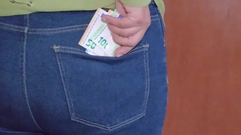 Close up view of hands putting folded euro banknotes into back jeans pocket Stock Footage 336984952