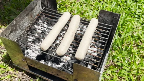 A close up view of hands putting sausages on the grill with kitchen tongs Stock Footage 281692236