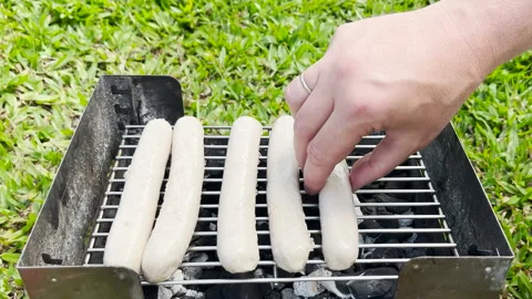 Close up view of hands putting sausages on the grill. Outdoor cooking concept Stock Footage 282320342