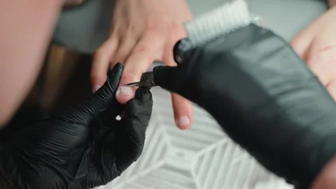Close-up view of hands receiving nail grooming. A person wears black gloves Stock Footage 339093866