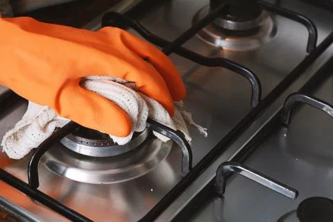 Close up view of hands in rubber gloves cleaning hob Foto stock