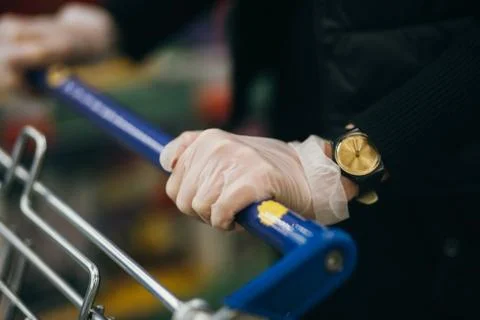 Close-up view of hands in rubber gloves pushing shopping carts. Stock-Fotos