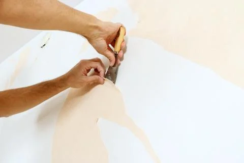 Close-up view on hands with a scraper in the process of removing wallpaper. Stock Photos