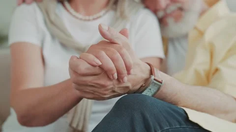 Close up view of a hands senior couple holding hands while resting on a couch Vídeos de archivo 224535344