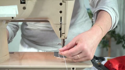 Close-up view of hands threading the needle of a vintage sewing machine, Stock Footage 336443920