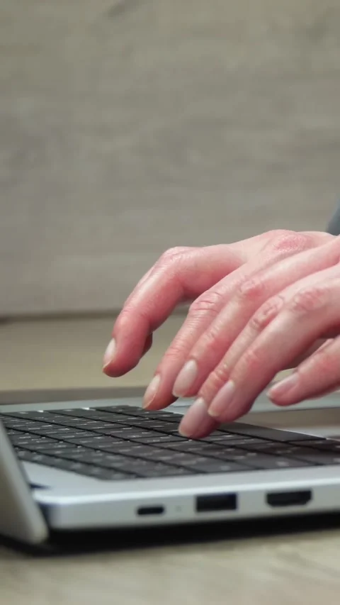 Close-up view of hands typing on laptop keyboard. Vertical composition captures Stock Footage 348195773