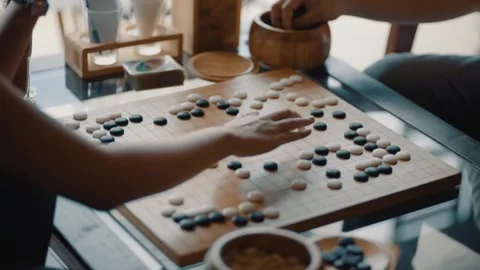 Close up view of hands young people playing go board game in living room	 Stock Footage 133444758