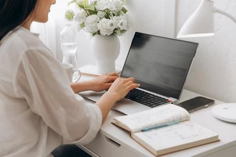 Close-up view on hands of young unrecognizable woman working on a laptop at a Stock Photos
