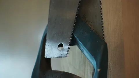 Close-up view of handsaw hanging on hook on wooden wall. Light shines into barn Stock Footage 160230425
