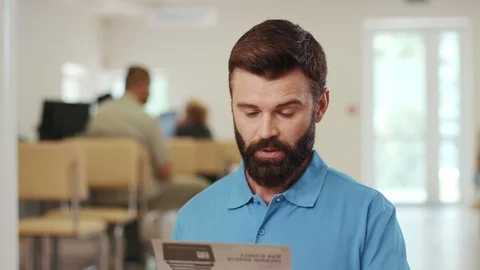 Close up view of handsome bearded man reading out loud the brochure Stock Footage 105257009