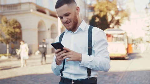 Close up view of handsome smiling man using his smartphone outdoors. Side view Stock Footage 115666890