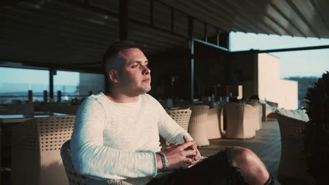 Close up view of handsome young man sitting in rooftop café, enjoying the view Stock Footage 112673965