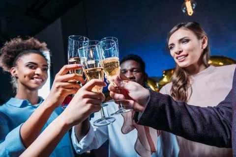 Close-up view of happy young multiethnic friends clinking champagne glasses Stock Photos