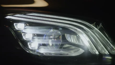 Close up view on headlights of prestigious black luxury modern car, lighting up Stock Footage 233787664