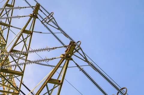 Close-up view of a high-voltage electricity pylon against a clear blue sky Stockfoto's