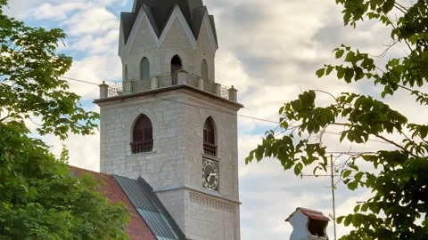 Close view of a historic church tower in Kranj, Slovenia, framed by green Stock Footage 339092146