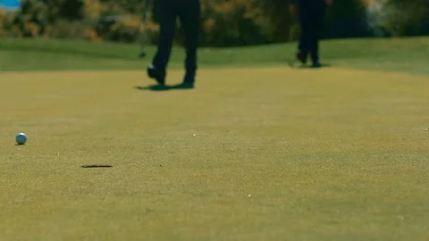 Close view hole putt misses left while players walk Stock-Footage 104298476