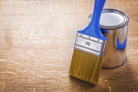 Close up view horizontal version paint brush with blue handle standing near can Fotos de archivo