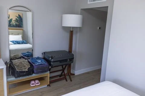 Close-up view of hotel room interior  with neatly folded clothing on suitcases. Stock Photos