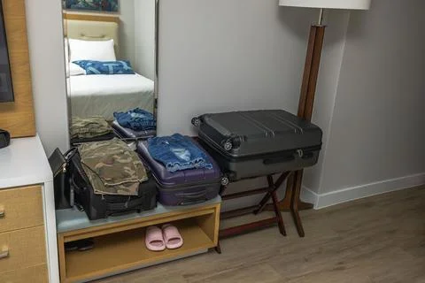 Close up view of hotel room interior with suitcases and unfolded clothes. Stock Photos