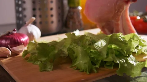 Close-up view of human hand putting a fresh beefsteak on a board with lettuce Video stock 107434494