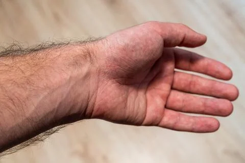 A close-up view of a human hand resting on wooden surface, showcasing details of Stock Photos