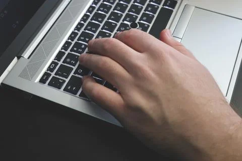 Close-up view of a human hand typing on a modern laptop keyboard Foto stock