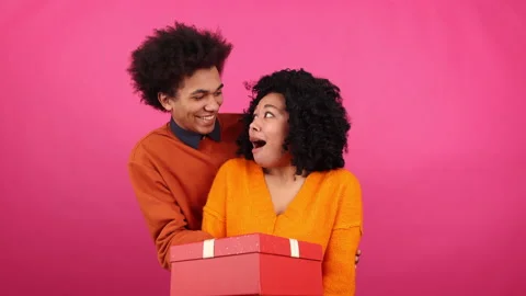 Close-up view of a husband presenting red gift box to his lovely wife Stock Footage 230110795