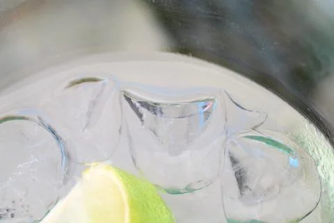 Close-up view of ice cubes and a fresh lime slice in a refreshing gin and t.. Stock Photos