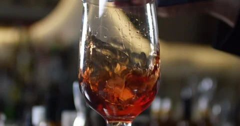 Close up view of ice cubes falling into glass with alcoholic cocktail. Close up Stock Footage 106470900