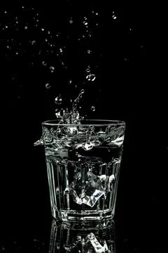 Close up view of the ice cubes splash in water are isolated on a black back.. Stock Photos