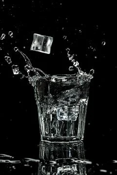 Close up view of the ice cubes splash in water are isolated on a black back.. Stock Photos