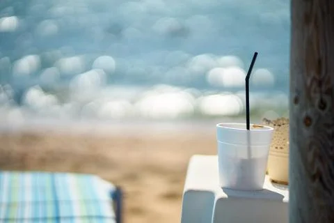 Close-up view of iced coffee in a plastic cup with a straw placed on a tabl.. Stock Photos