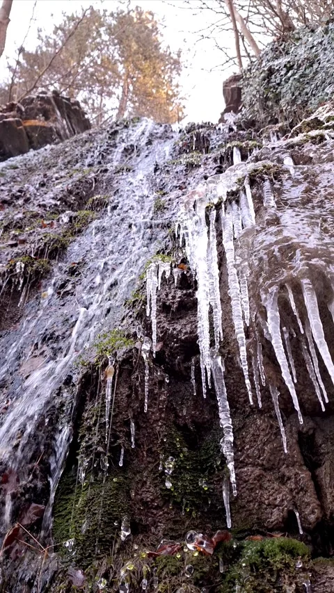 A close-up view of icicles melting by a waterfall Stock Footage 294541639