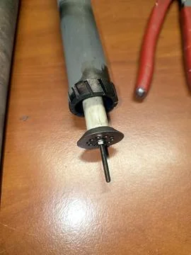 A close view of an industrial igniter part placed on a workbench. Nearby tool Stock Photos