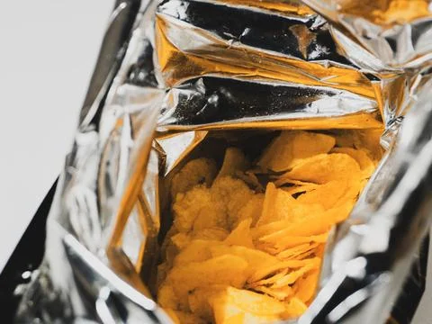 Close up view inside an open bag of golden potato chips Foto stock