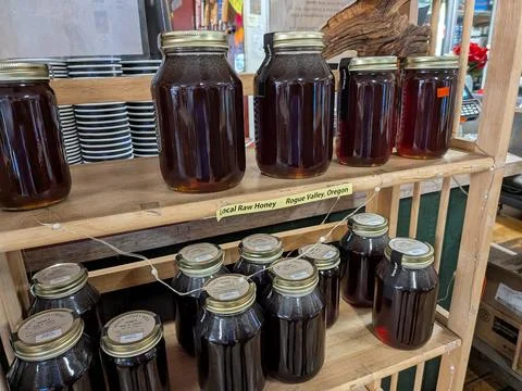 Close view of jars labeled local raw honey on indoor shelf Foto stock