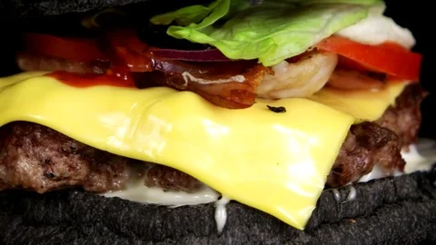 Close-up view of juicy black burger with meat, cheese, loop Stock Footage 75253763