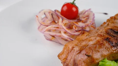 Close-up view of juicy pork chop with tomato and onion Stock Footage 79713465