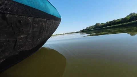 Close view of a kayak gliding across calm river water under a clear sky. Ideal Stock Footage 344817285