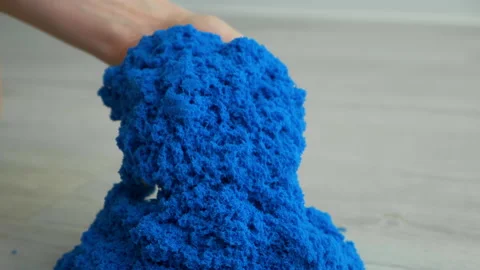 Close-up view kinetic sand of bright blue color for play in woman's hands. Video stock 168222915